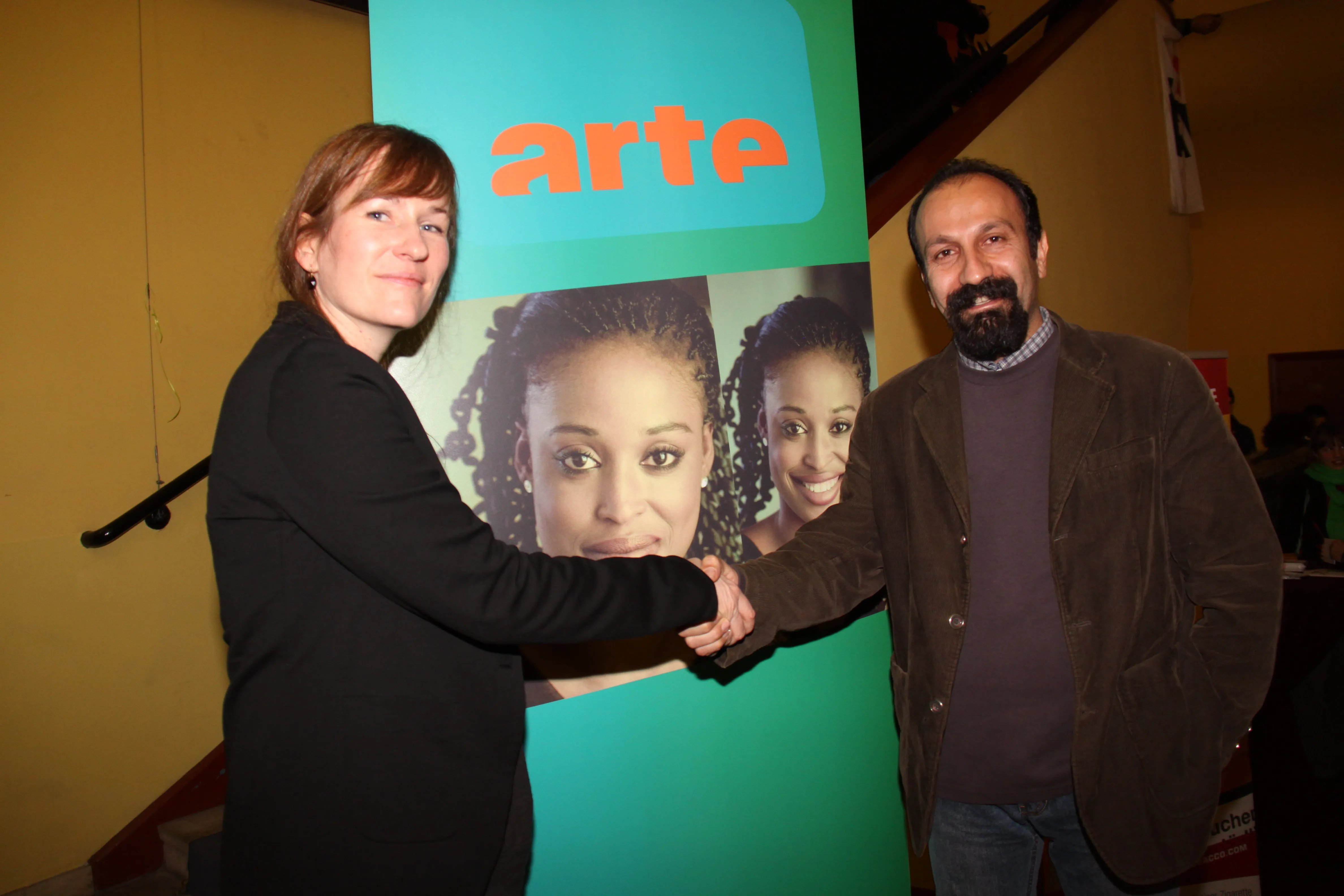 Zwei Personen geben sich vor einem arte-Aufsteller die Hand.