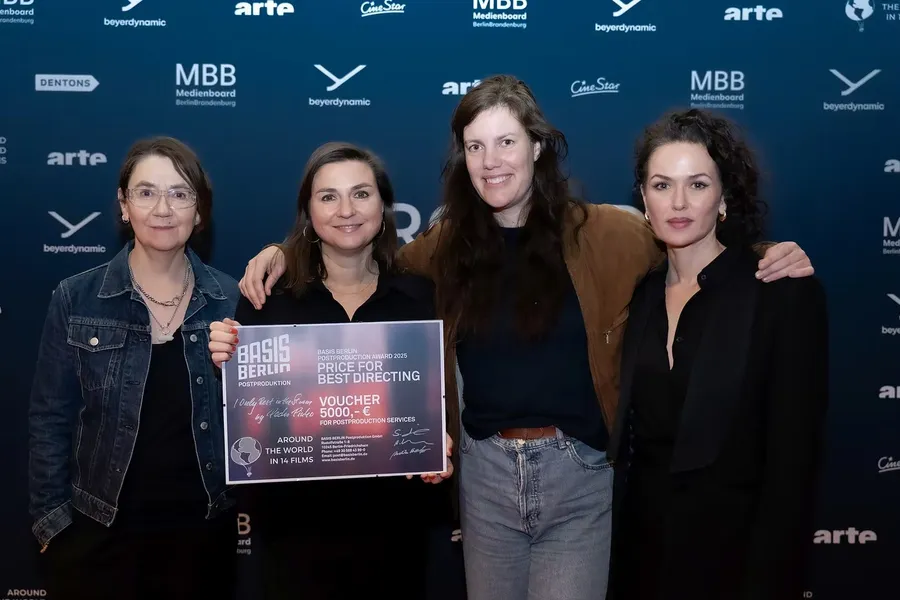 The jury holding the certificate of the BASIS Berlin Postproduction Award in front of the photo wall