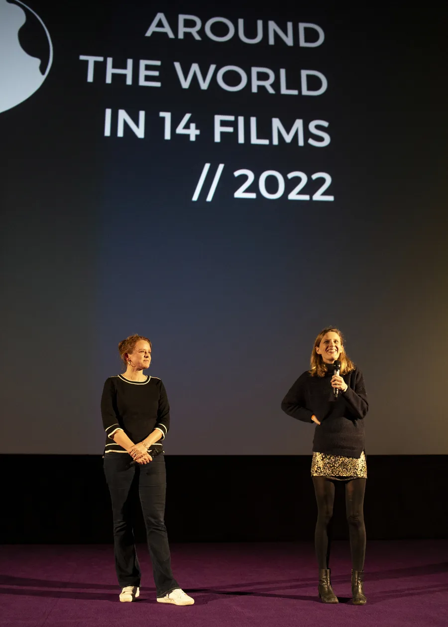 Two people on stage in front of the screen bearing the festival's 2022 lettering