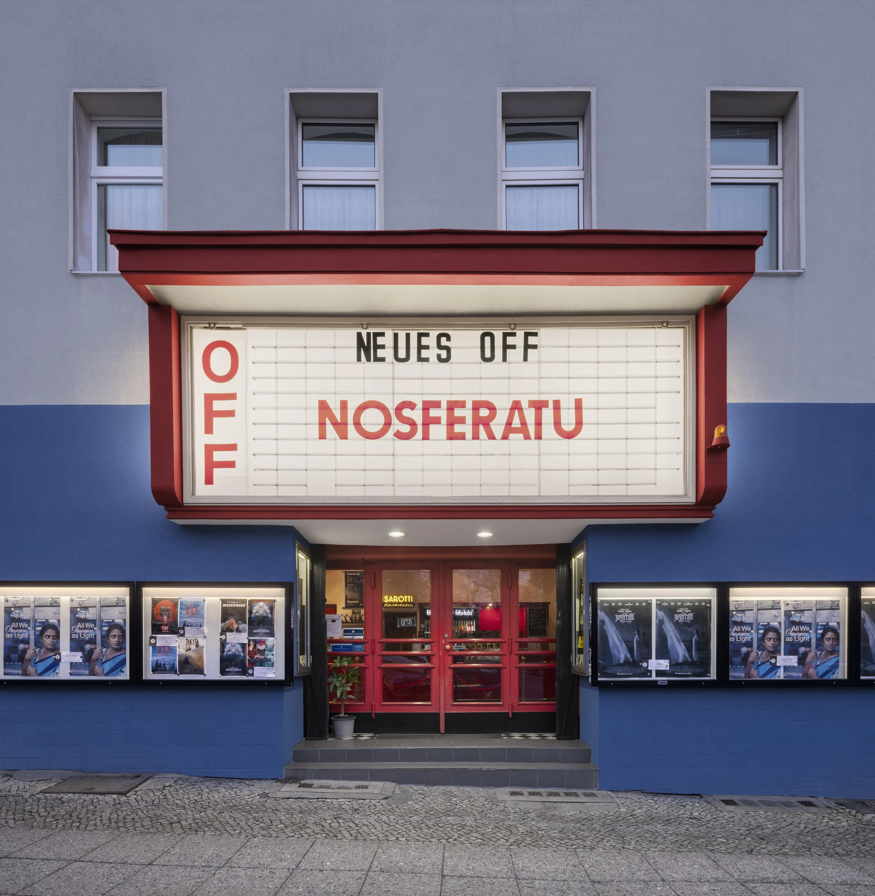 Fassade des Neuen Off mit beleuchtetem Schriftzug am Abend