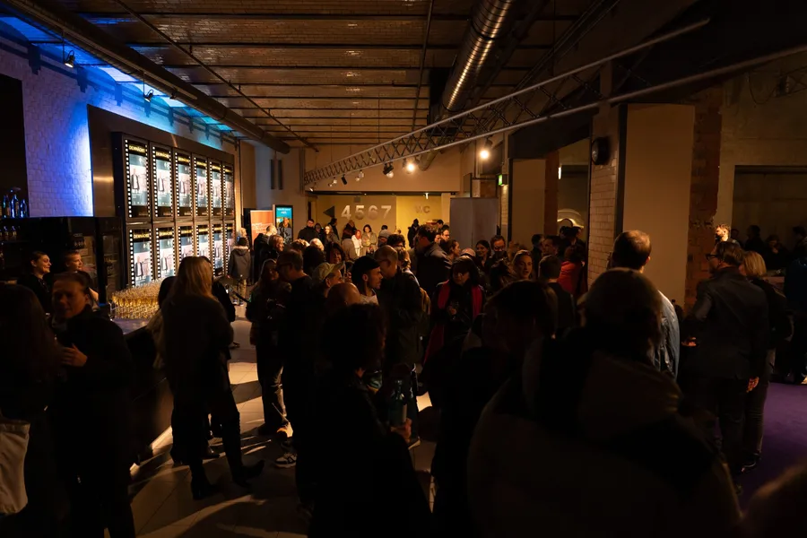 A full foyer after a screening, glasses on the bar, conversations in small groups
