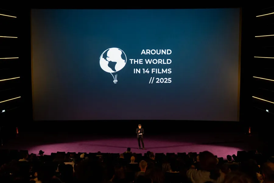 A full house, the festival logo on the screen, a person speaking on stage in front of it